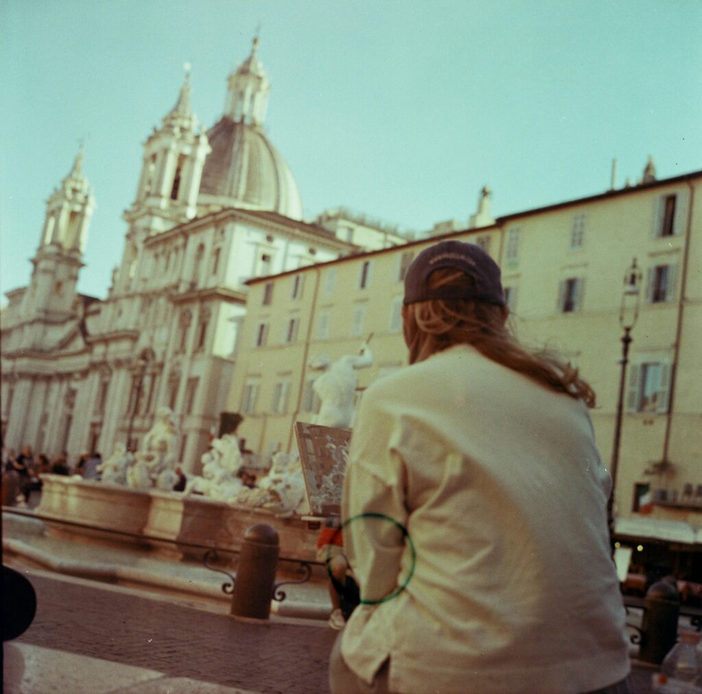 A tourist enjoys the view of Piazza Navona, Rome, highlighting its iconic architecture.